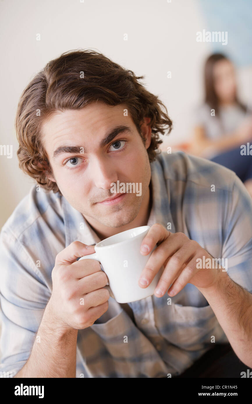 USA, Californie, Los Angeles, Portrait of young man holding mug, woman in background Banque D'Images