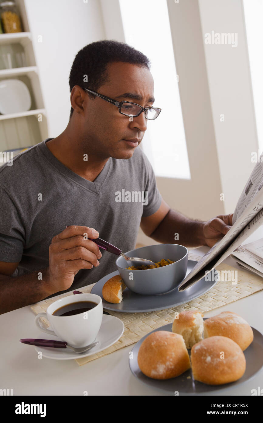 USA, Californie, Los Angeles, Mature man eating breakfast and reading newspaper Banque D'Images
