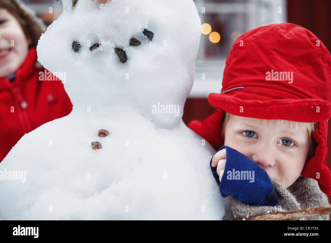 Close up of boy hugging snowman Banque D'Images