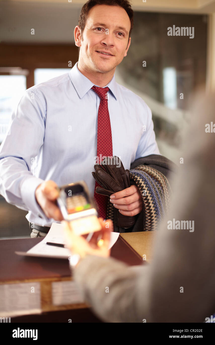Businessman payer à réception de l'hôtel Banque D'Images