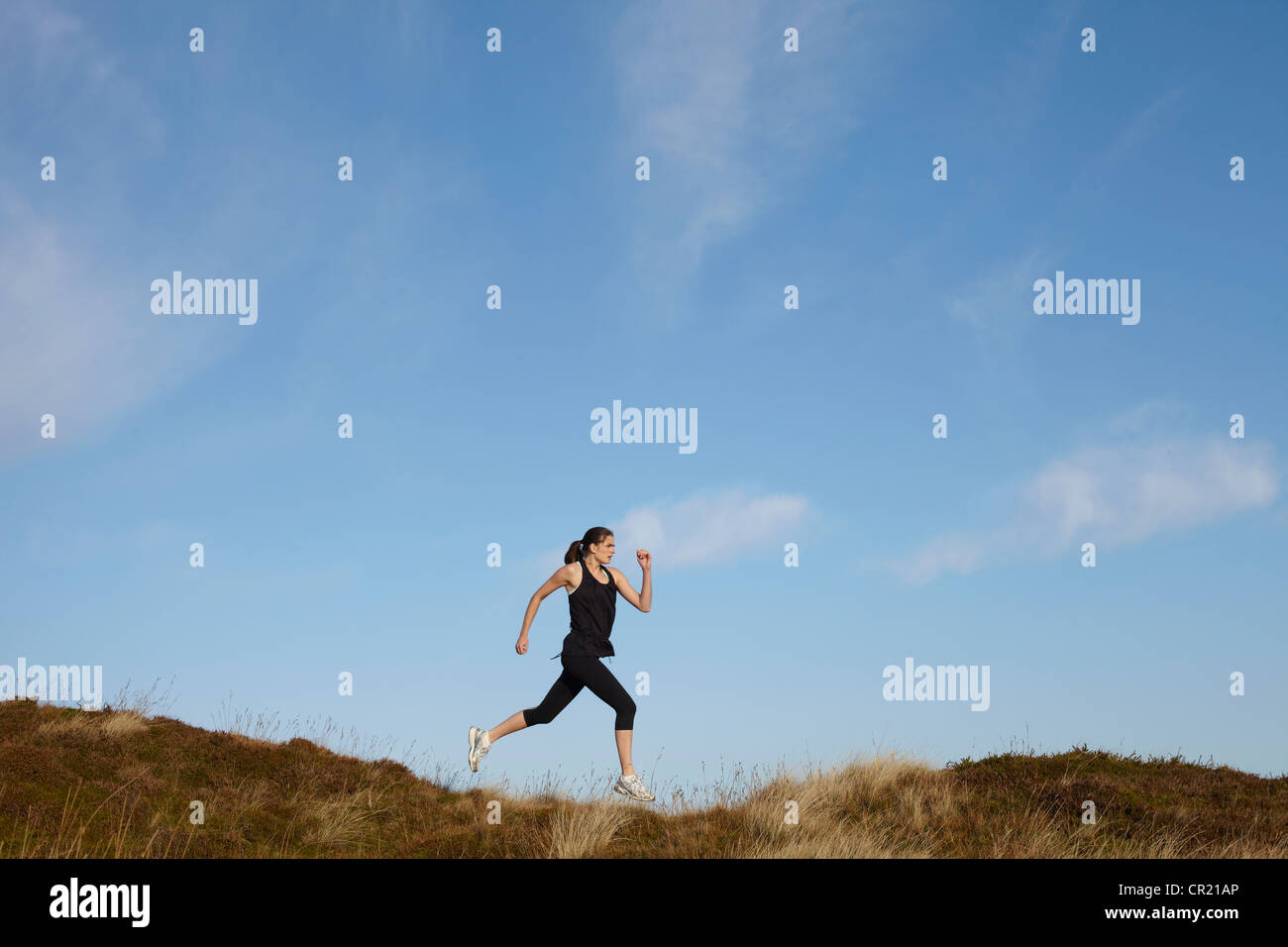 Woman running on rural hillside Banque D'Images