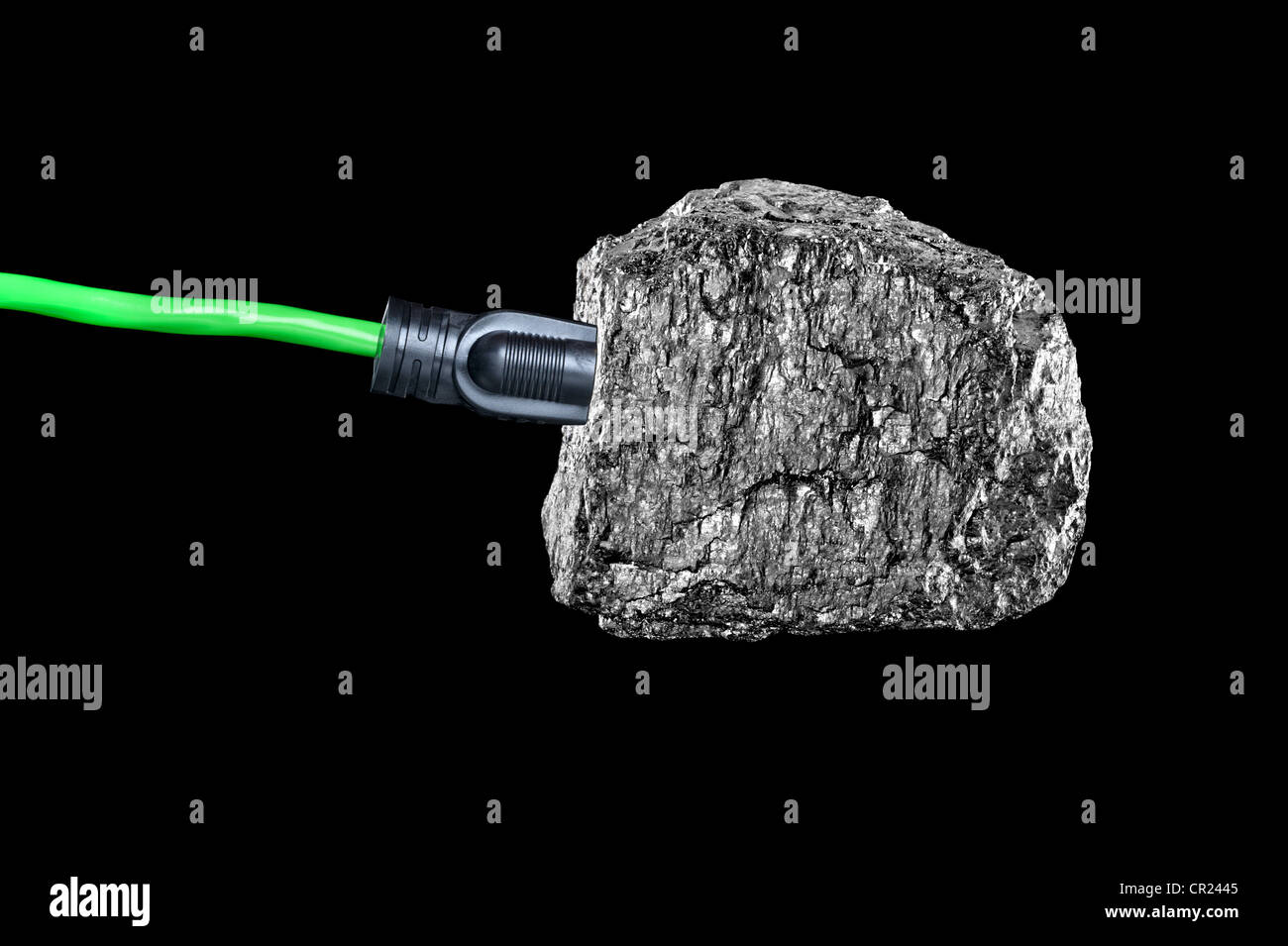 Une image conceptuelle d'une rallonge branchée sur un morceau de charbon bitumineux isolé sur noir. Banque D'Images