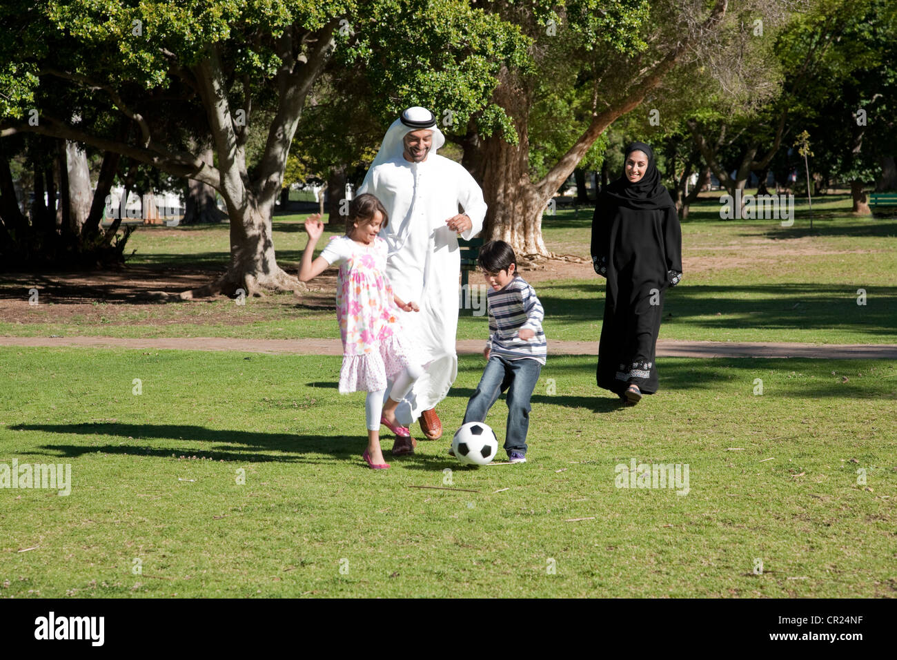 Famille arabe jouant au football ensemble au parc. Banque D'Images