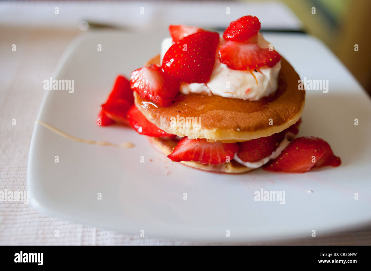 Les fraises servi sur des crêpes avec crème fraîche arrosée de miel pour un petit-déjeuner sain Banque D'Images
