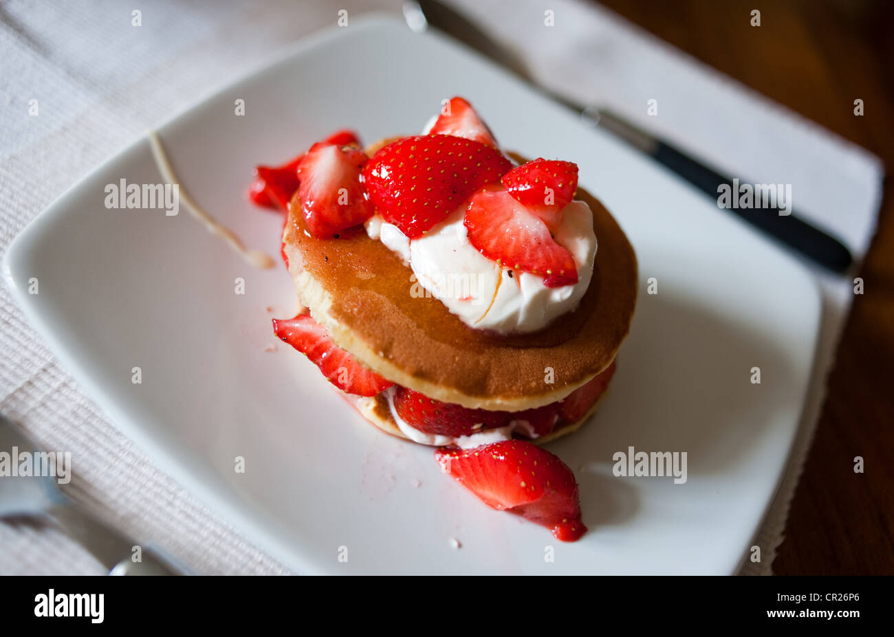 Les fraises servi sur des crêpes avec crème fraîche arrosée de miel pour un petit-déjeuner sain Banque D'Images