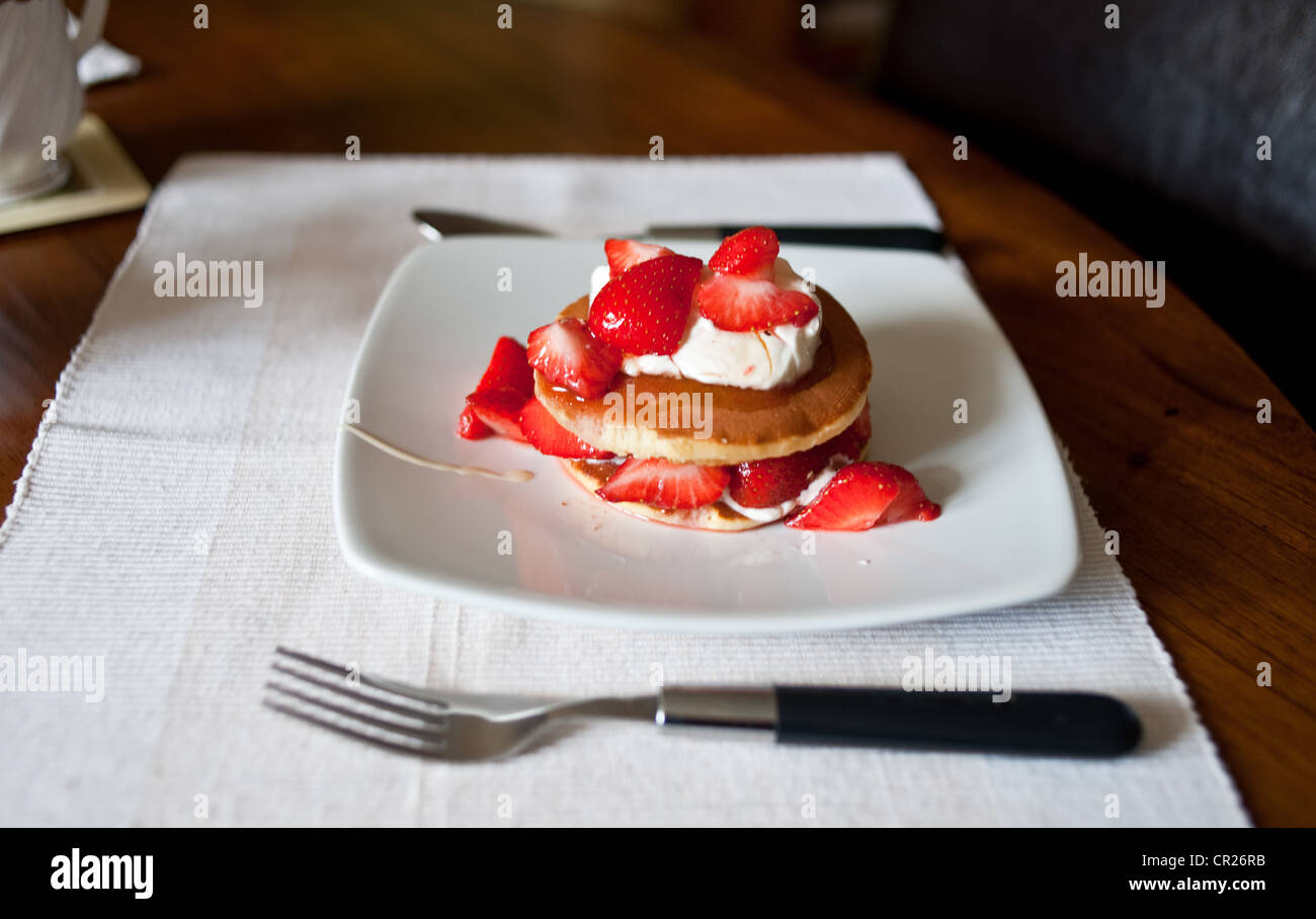 Les fraises servi sur des crêpes avec crème fraîche arrosée de miel pour un petit-déjeuner sain Banque D'Images