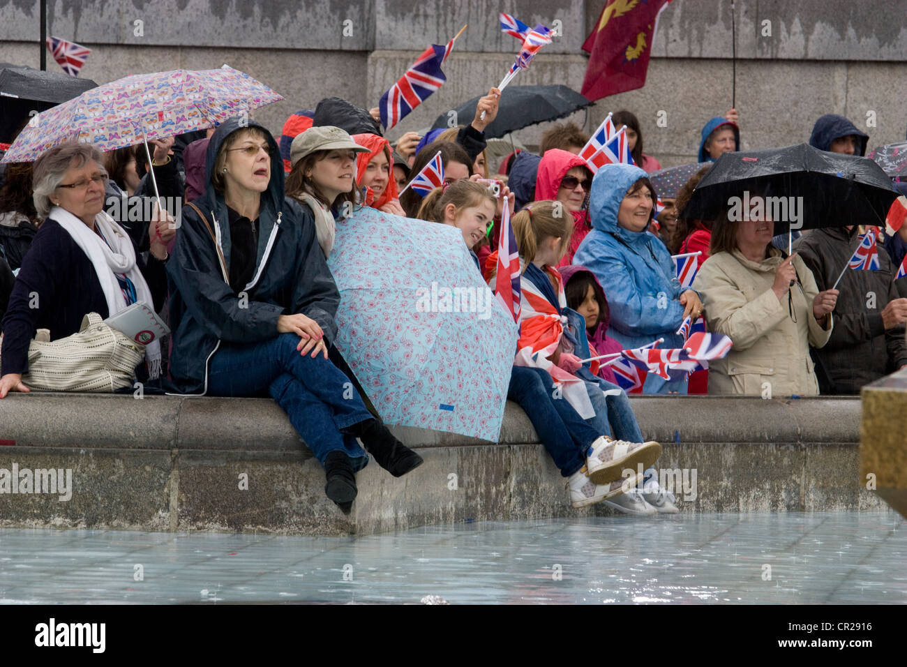 Royal queens diamond jubilee 2012 fêtards, à l'abri dans la pluie par fontaine dans Trafalgar Square London Banque D'Images