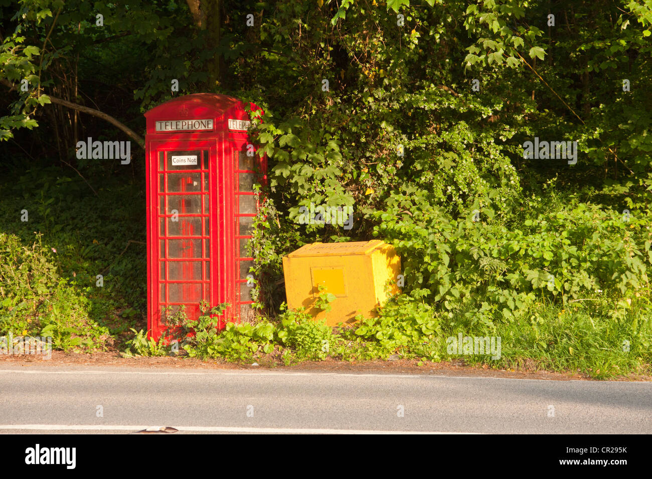 Old fashioned red telephone box avec grain jaune conteneur sur Devon country road. Banque D'Images