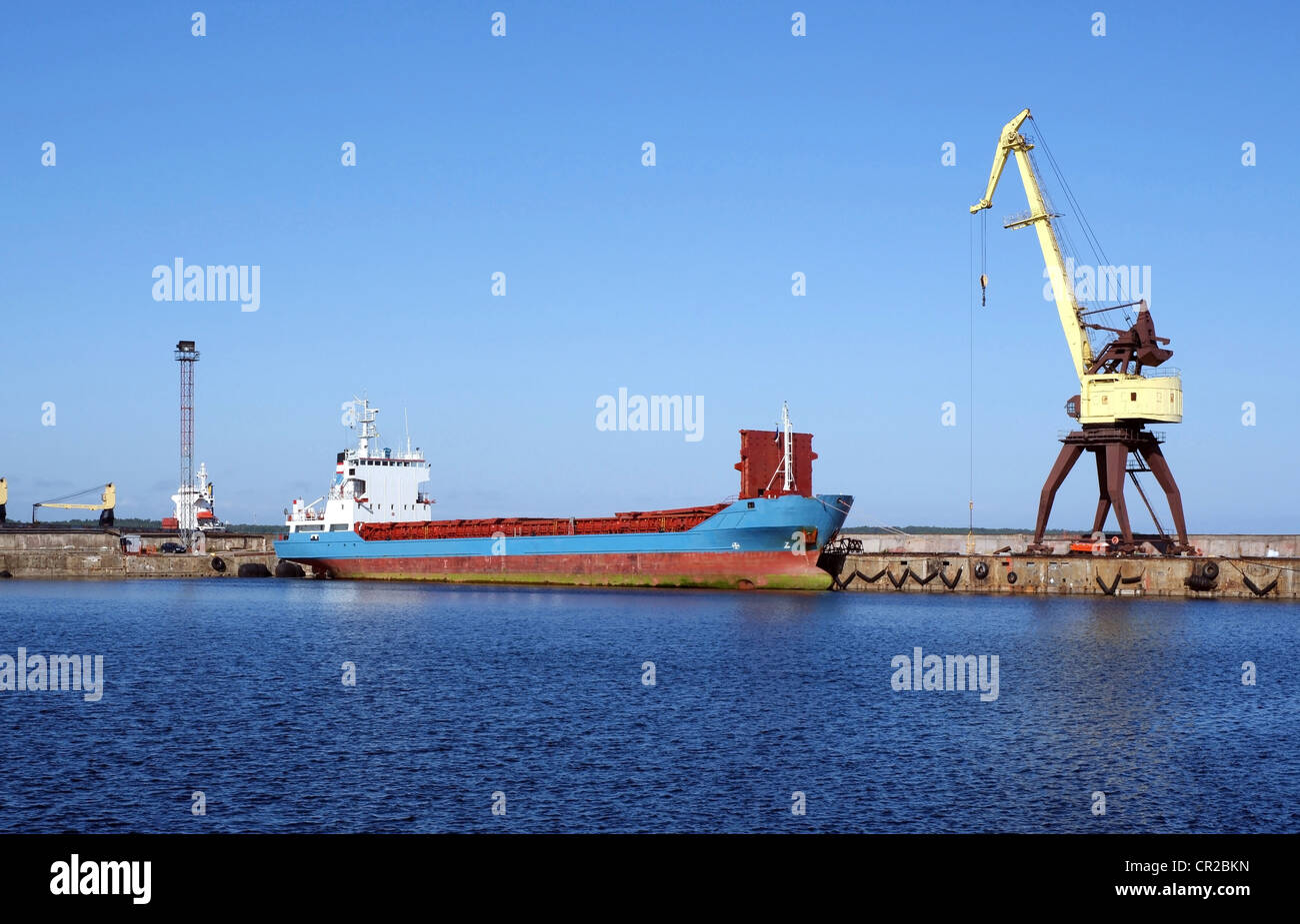 Le cargoship et la grue sur un arrière-plan du ciel bleu Banque D'Images