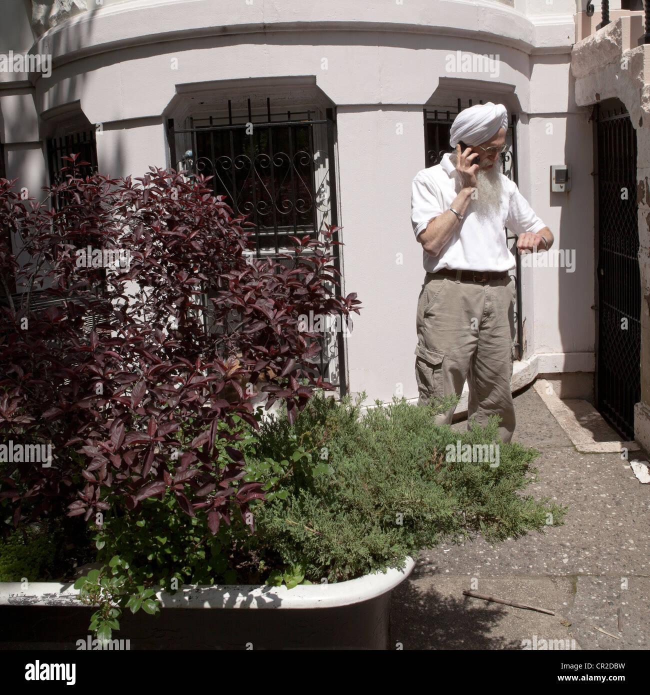 Un yogi barbu parle sur son téléphone à l'extérieur de sa maison à Brooklyn, New York. Banque D'Images