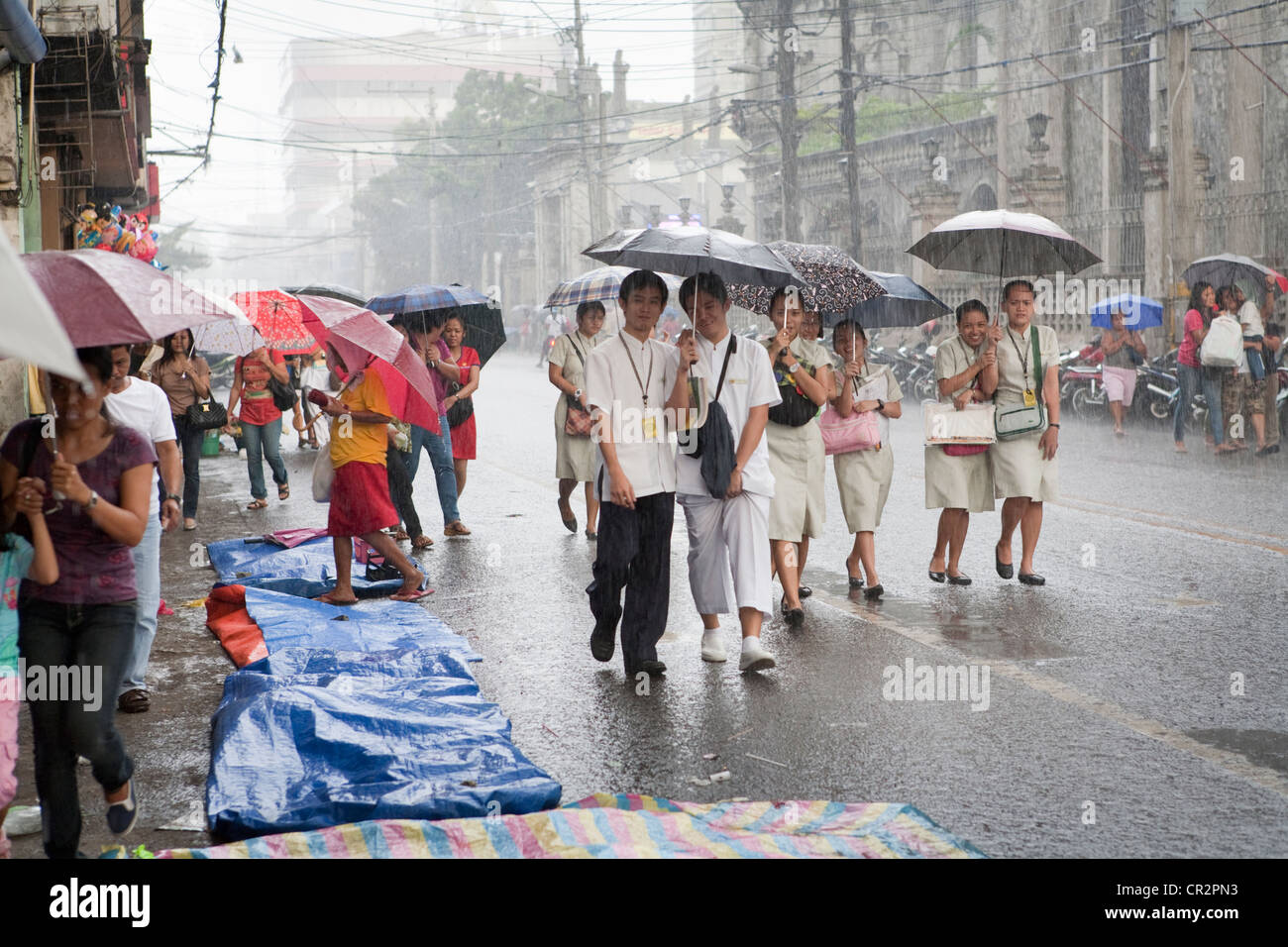 Les étudiants du collège à pied lors d'une forte pluie. La ville de Cebu, Cebu, Visayas, Philippines. Banque D'Images