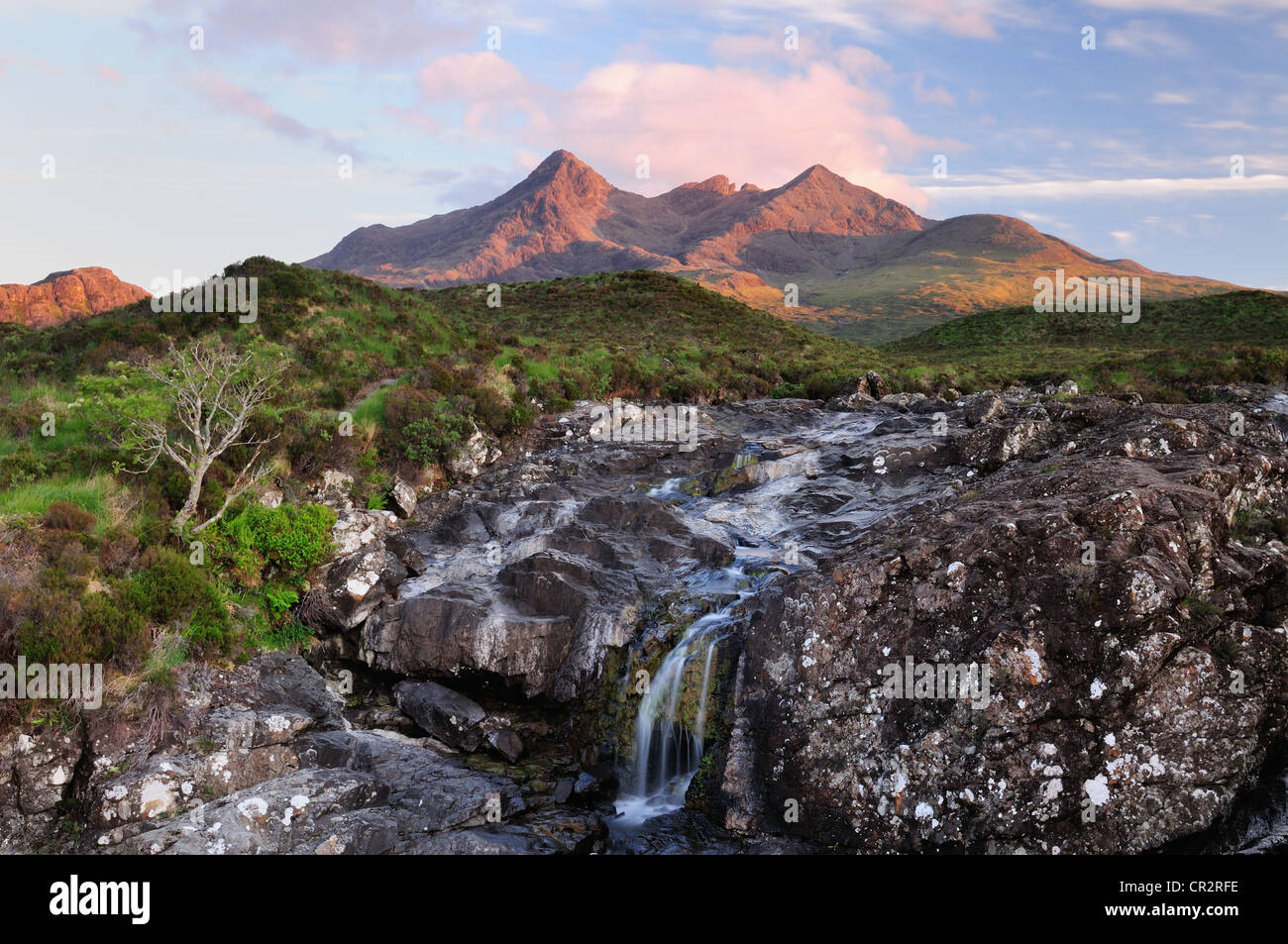 Cascade sur l'Allt Dearg Mor, avec les sommets de l'ensoleillée Black Cuillin Hills dans l'arrière-plan Banque D'Images