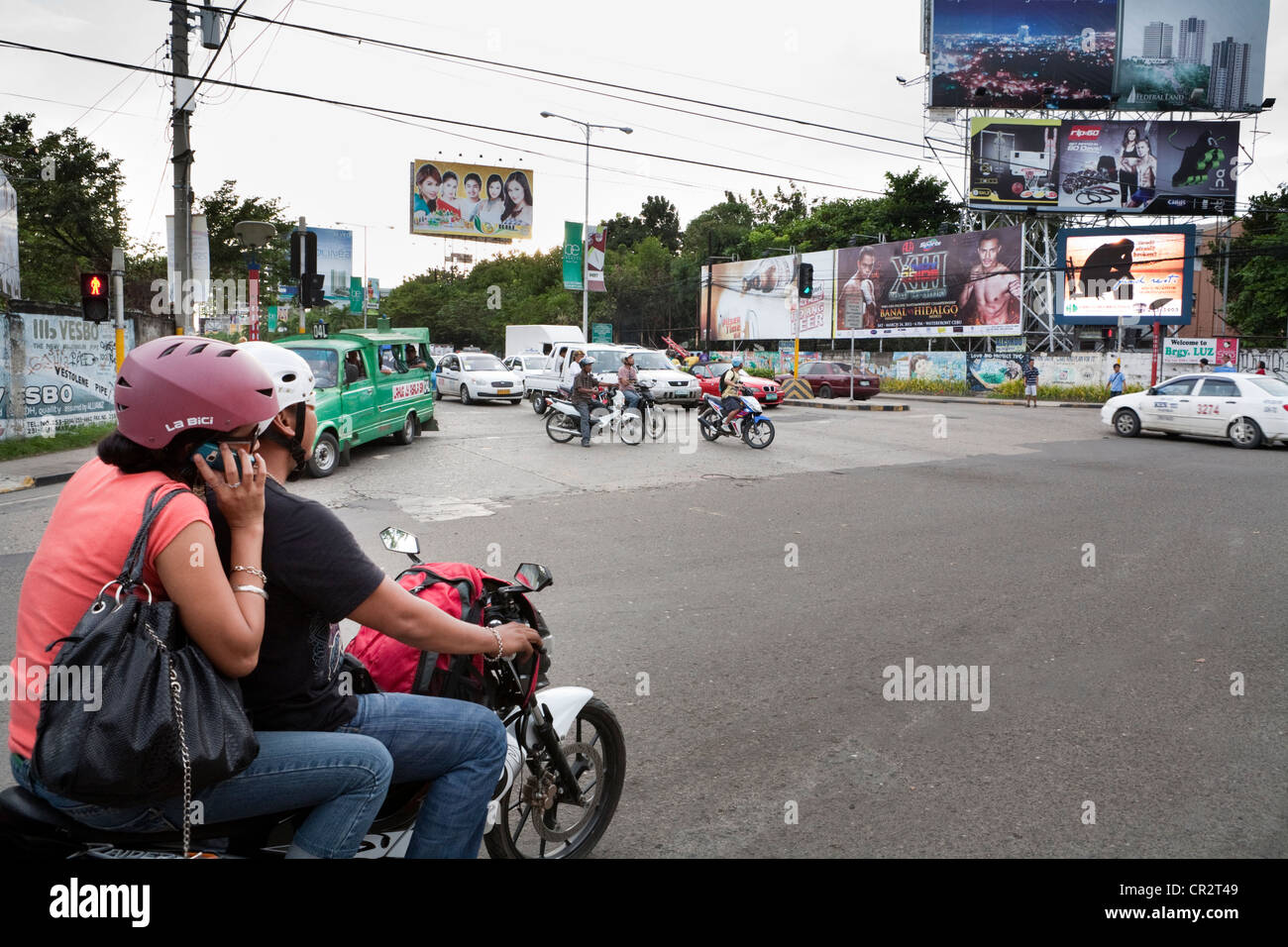 Passagère de parler sur un téléphone mobile, les panneaux publicitaires à un carrefour. La ville de Cebu, Cebu, Visayas, Philippines. Banque D'Images