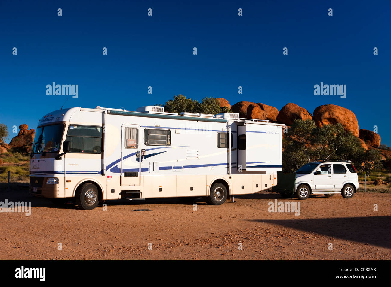 Un camping-car, avec une voiture à l'arrière, garé sur un emplacement de camping, Devils Marbles, Territoire du Nord, Australie Banque D'Images