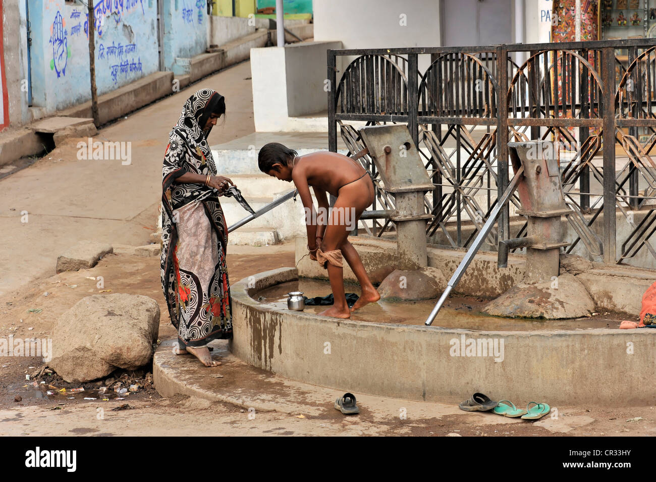 Mère indienne lave son fils dans une fontaine du village, Orchha, Madhya Pradesh, Inde du Nord, Inde, Asie Banque D'Images