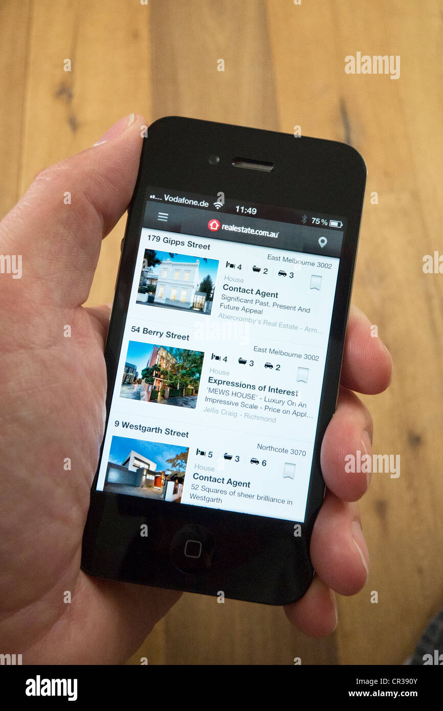 À l'aide d'un iPhone 4G téléphone intelligent pour trouver une maison à acheter à Melbourne en Australie en utilisant des biens trouver App Banque D'Images