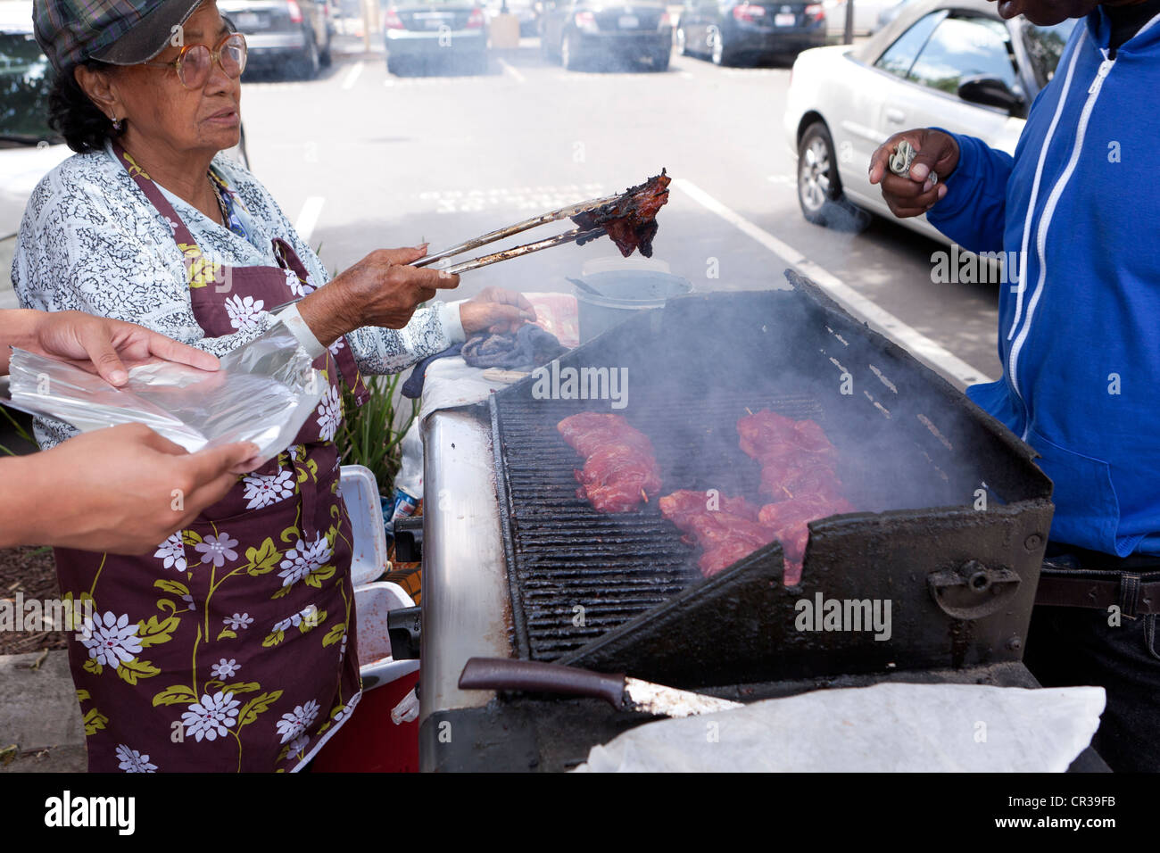 Une femme âgée d'un barbecue en plein air Banque D'Images