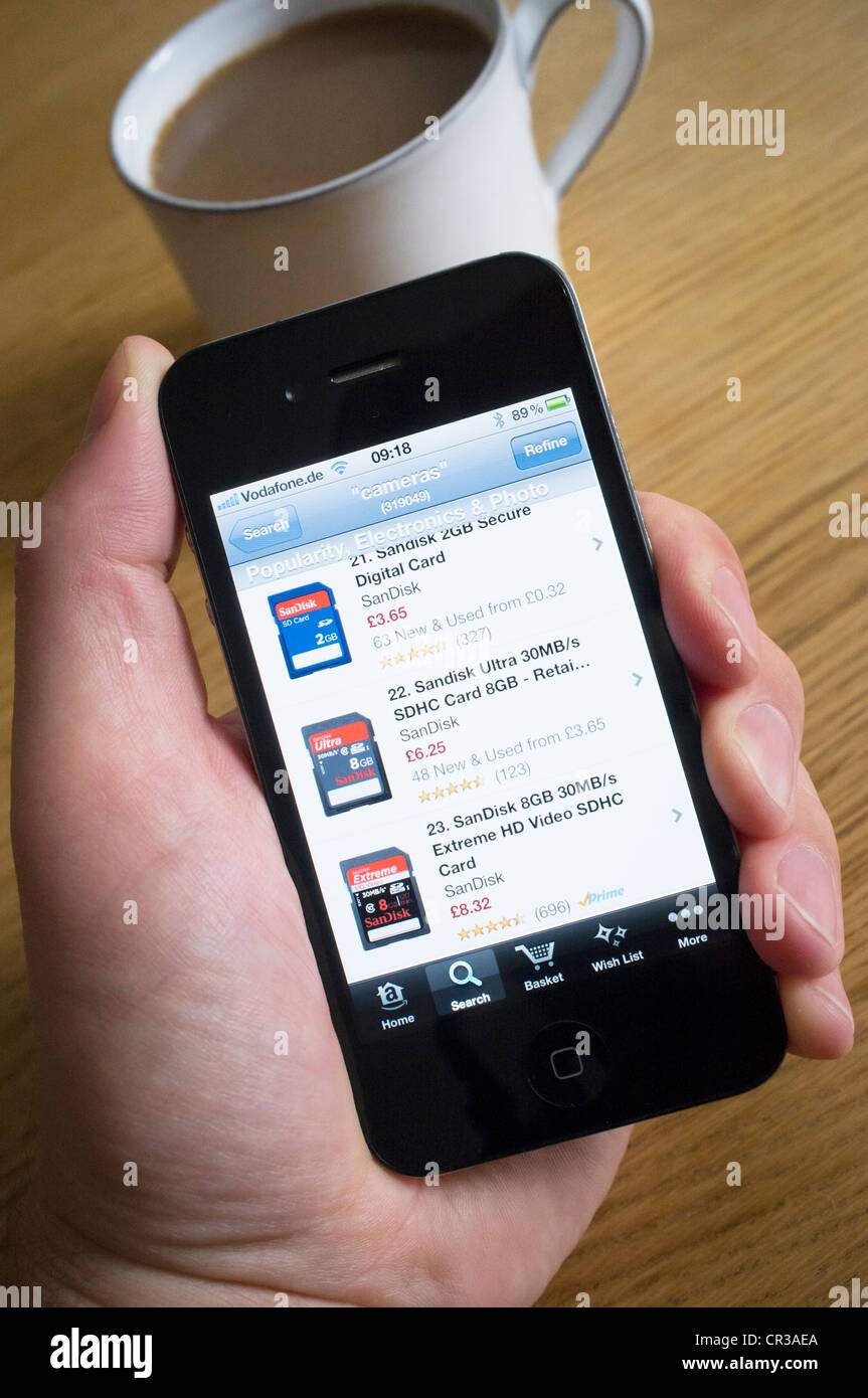 À l'aide d'un iPhone 4G téléphone intelligent pour acheter des produits de l'électronique de Amazon.com boutique en ligne Banque D'Images