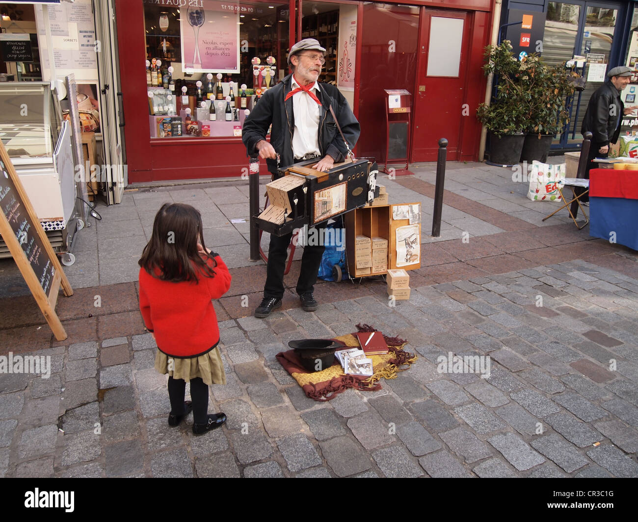 Orgue de Barbarie joue pour de l'argent en petite fille regarde, sur la Rue Cler à Paris, France, 10 mai 2012, © Katharine Andriotis Banque D'Images