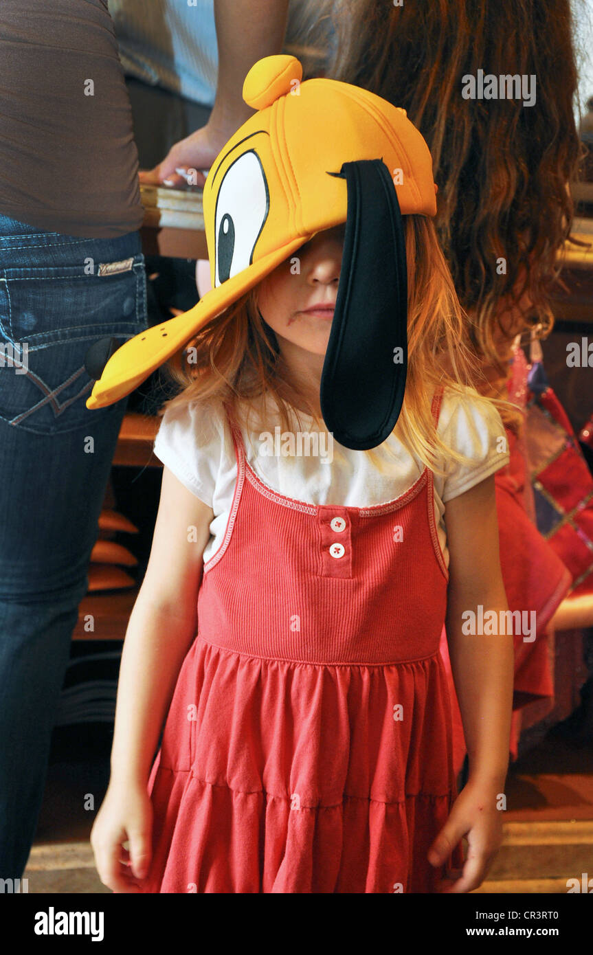 Petite fille joue avec Dingo Hat couvrant le visage à Hat shop au Parc Disneyland, Anaheim, Californie Banque D'Images