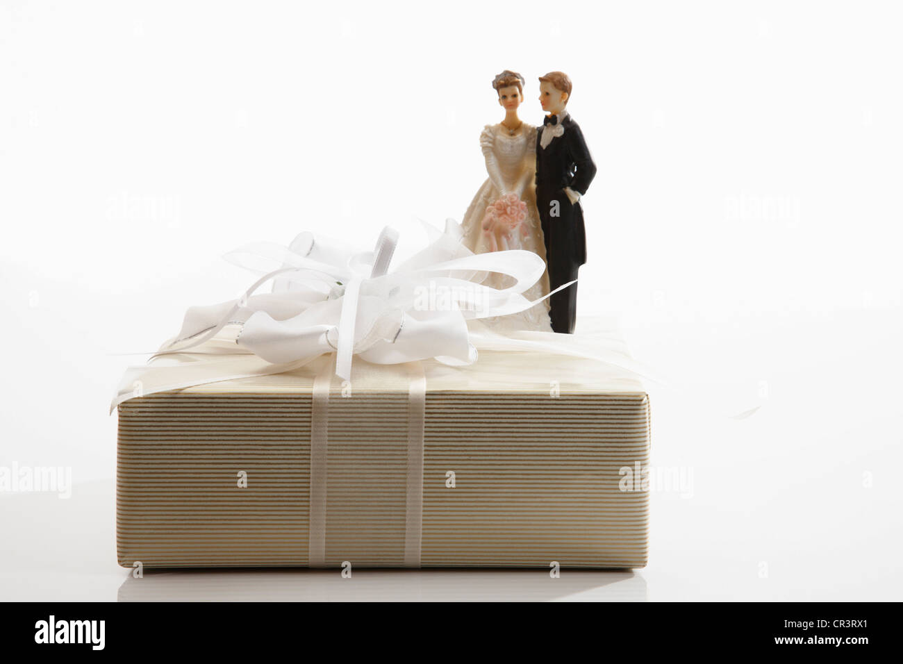 Cadeau de mariage, cadeau avec un arc blanc et un couple mariée miniature Banque D'Images