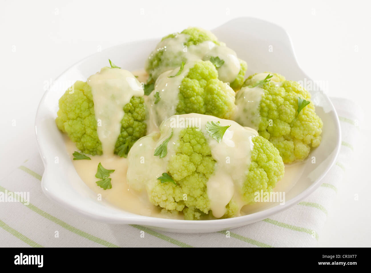 Chou-fleur vert avec sauce au fromage et une pincée de persil frais, dans une assiette blanche. Banque D'Images