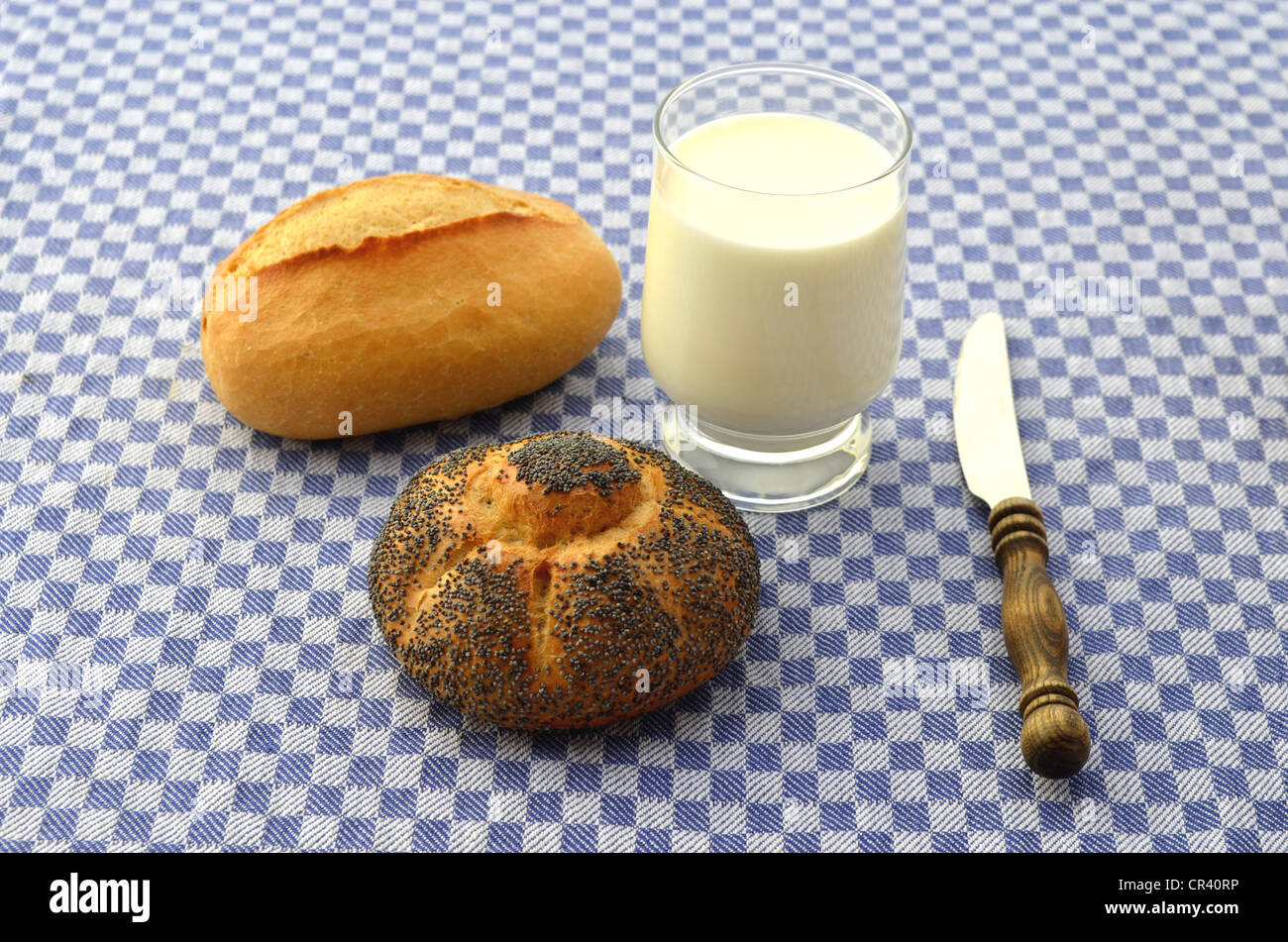 Rouleaux, rouleau de graines de pavot avec un verre de lait frais, petit-déjeuner couteau avec un manche en bois Banque D'Images