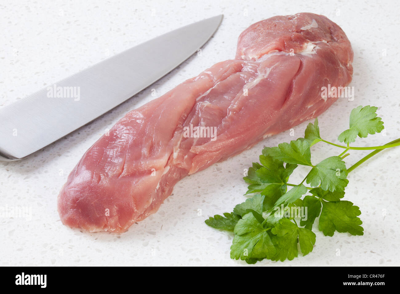 Tenderfloin de porc cru ou filet de porc sur surface de granit, avec du persil et de la lame. Banque D'Images