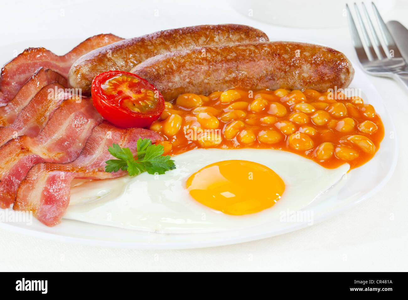 Le petit déjeuner anglais complet, avec bacon, saucisses, deux un œuf frit, haricots blancs et une moitié de tomate. Banque D'Images
