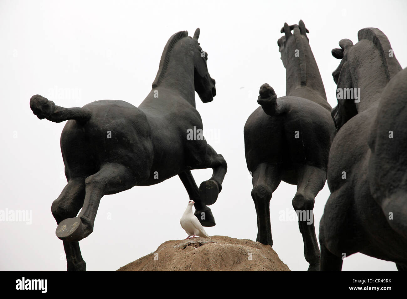 C'est une photo de statues de chevaux faits à partir du fer ou d'acier ou de cuivre. Ils sont debout sur un gros rocher au milieu d'une ville. Ils courent Banque D'Images