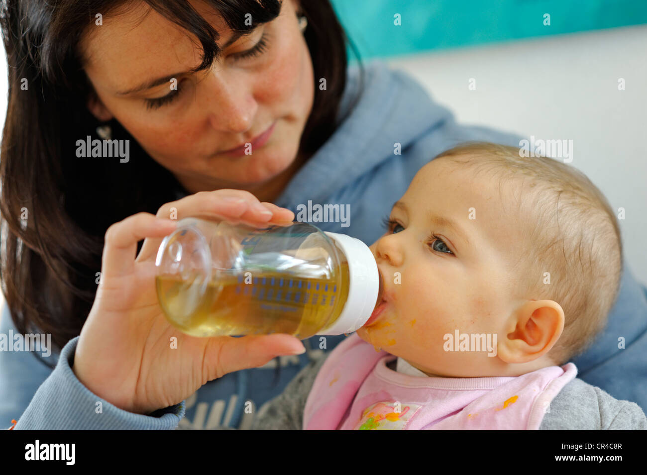 Six mois, bébé, boire d'une bouteille tenue par sa mère Banque D'Images