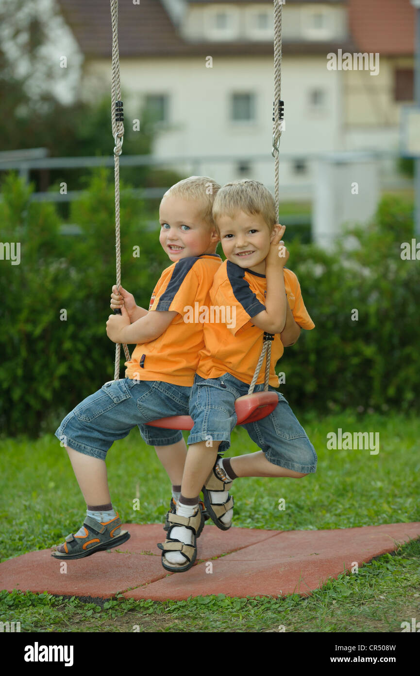 Deux petits garçons, 3 et 4 ans, sur une balançoire Banque D'Images
