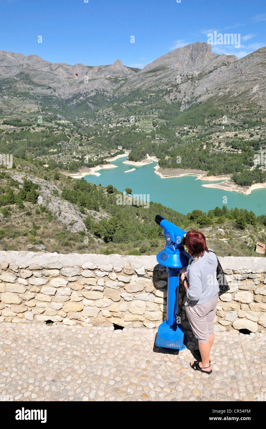 Femme à un télescope avec une vue sur le lac de stockage de Guadalest, Costa Blanca, Espagne, Europe Banque D'Images