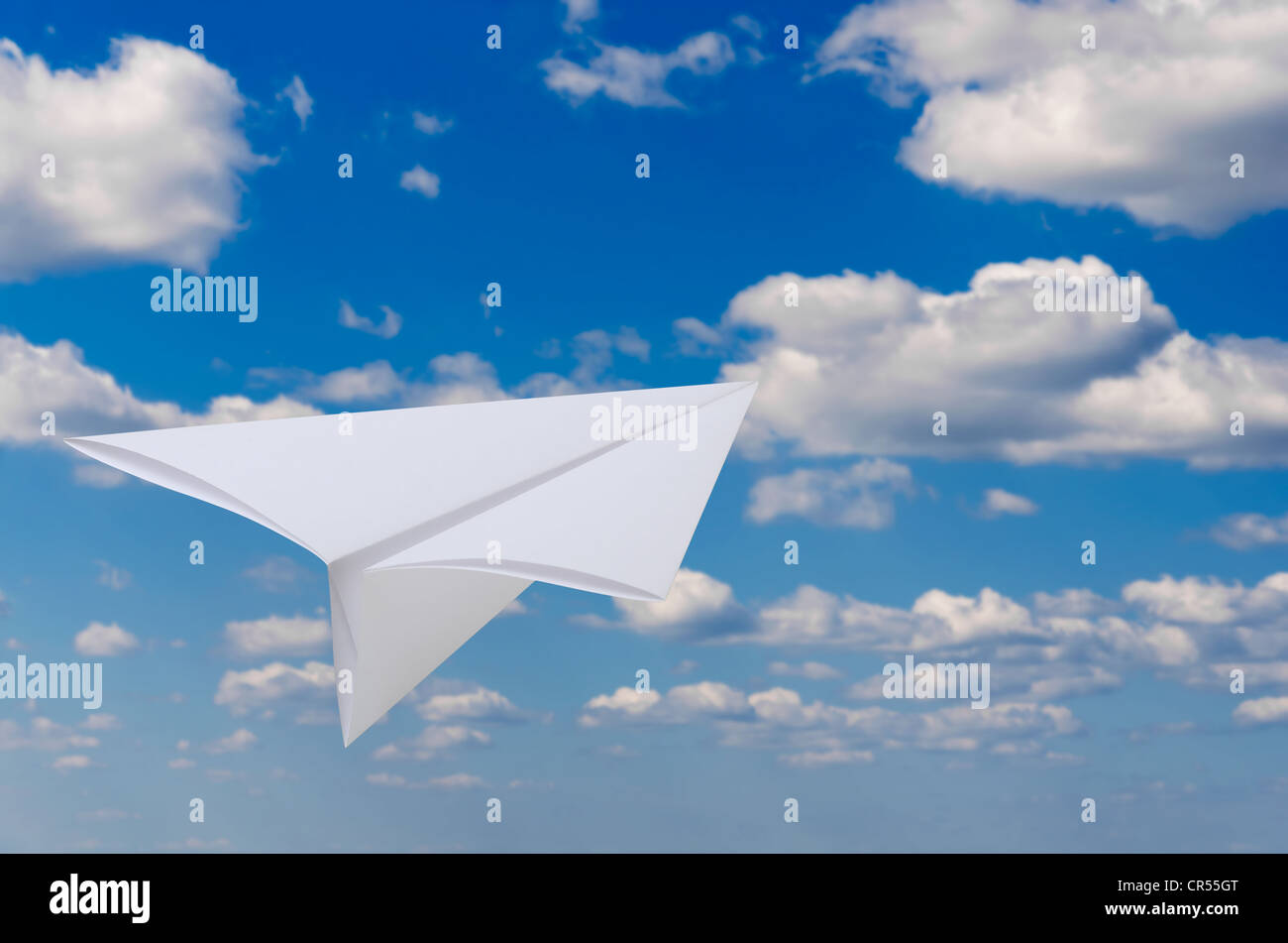 Vol d'un avion de papier contre le ciel bleu et nuages Banque D'Images