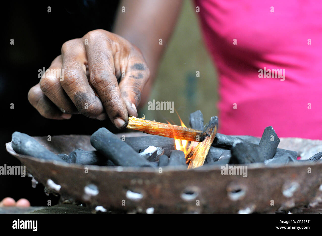 Femme d'allumer un feu dans un poêle à charbon pour la cuisson, cabaret, Haïti, Caraïbes, Amérique Centrale Banque D'Images