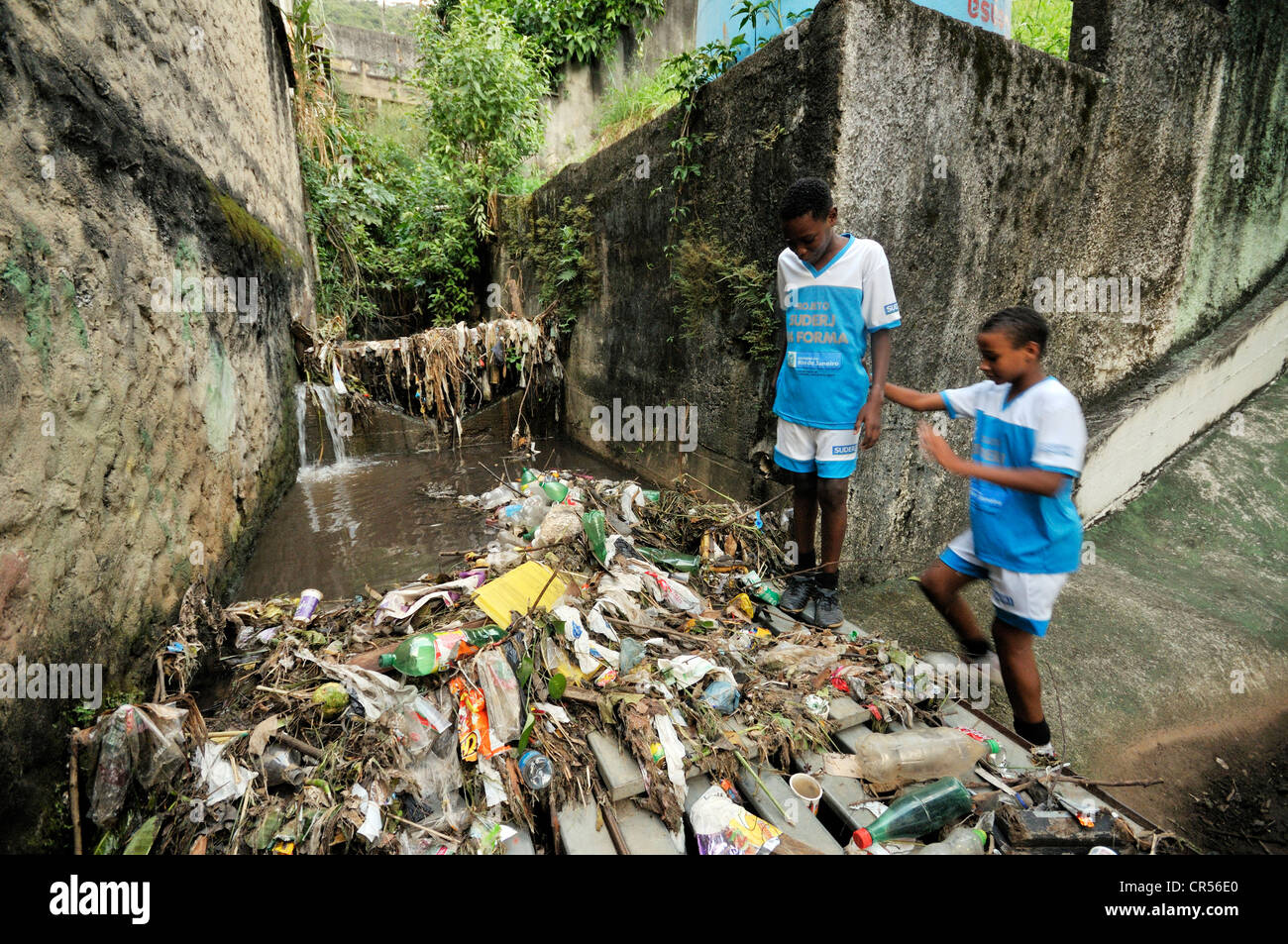 Les résidents du bidonville district de Favela Morro da Formiga debout à côté de déchets dans un canal d'égout exposés, quartier de Tijuca Banque D'Images
