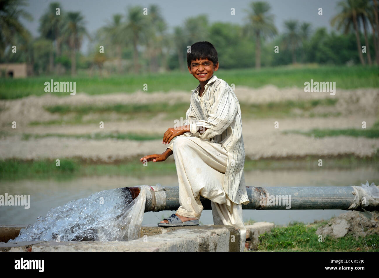 Garçon debout à l'échelle d'un ressort qui est alimentée par une conduite d'eau, Lehar Basti Walla village, Punjab, Pakistan, Asie Banque D'Images