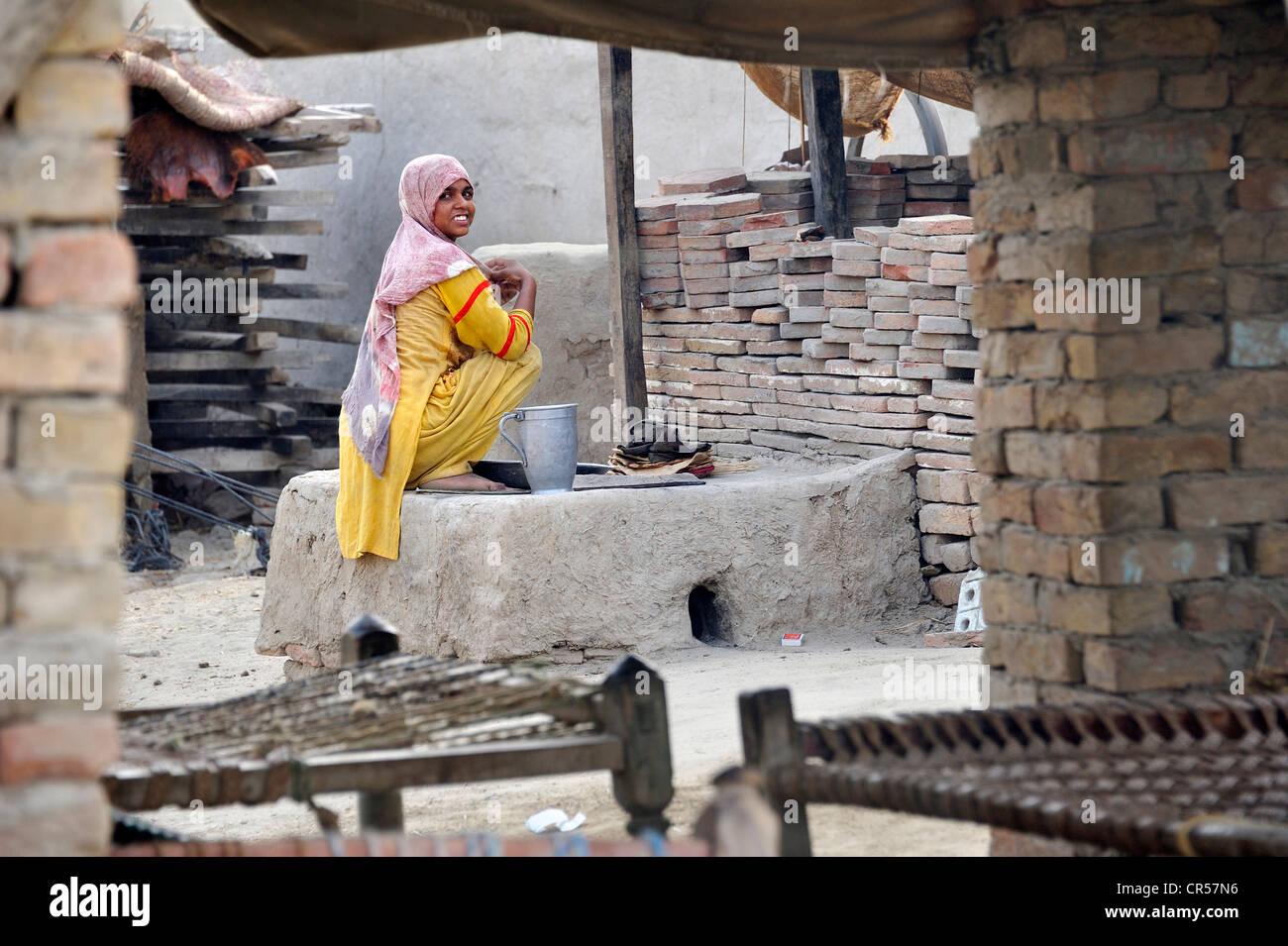 Jeune femme assise par un four pour la cuisson du pain, Lehar Basti Walla village, Punjab, Pakistan, Asie Banque D'Images