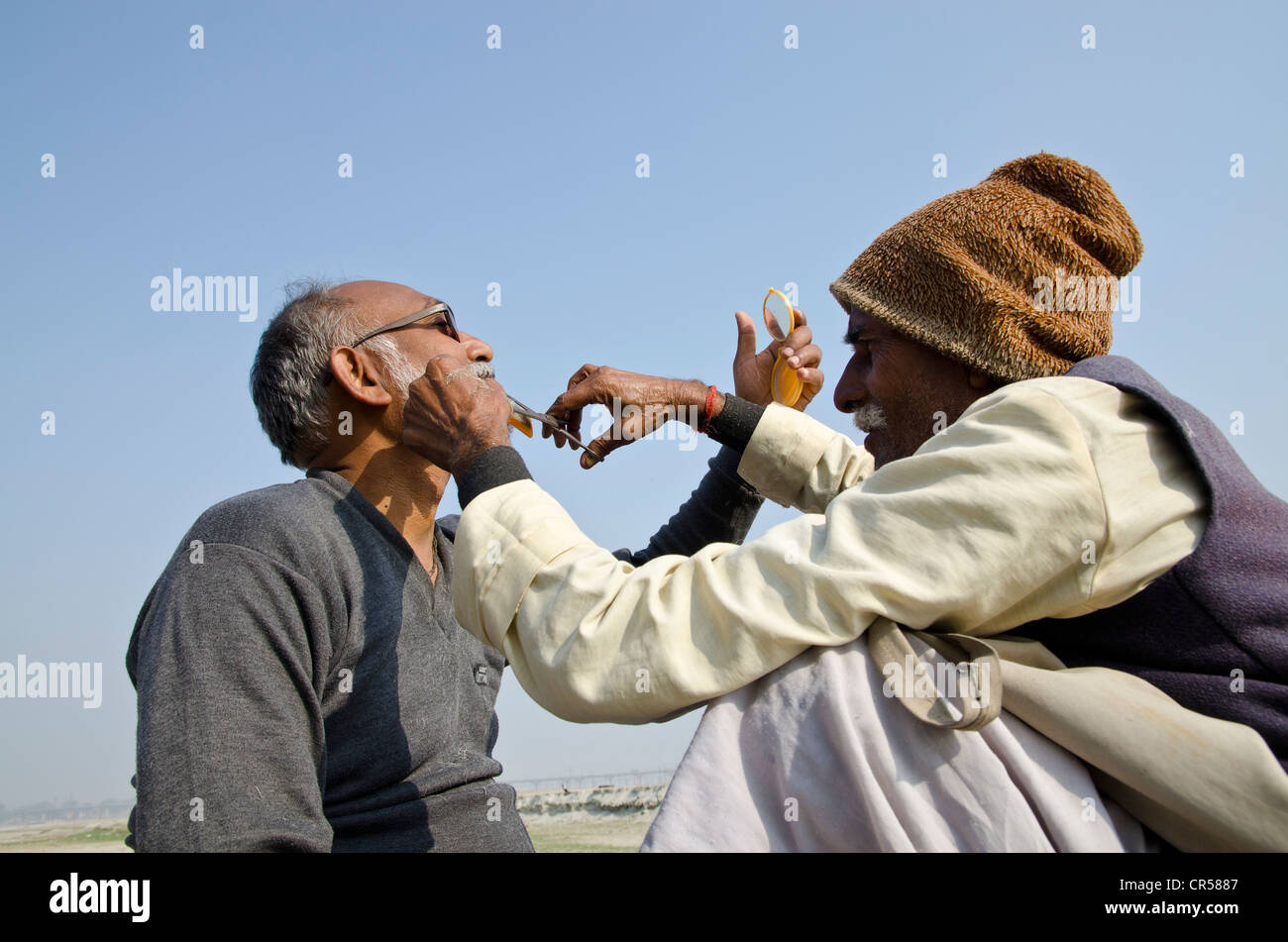 La tête de rasage dans le cadre d'un rituel religieux, effectuée à Sangam, la confluence des rivières saint Ganges Banque D'Images