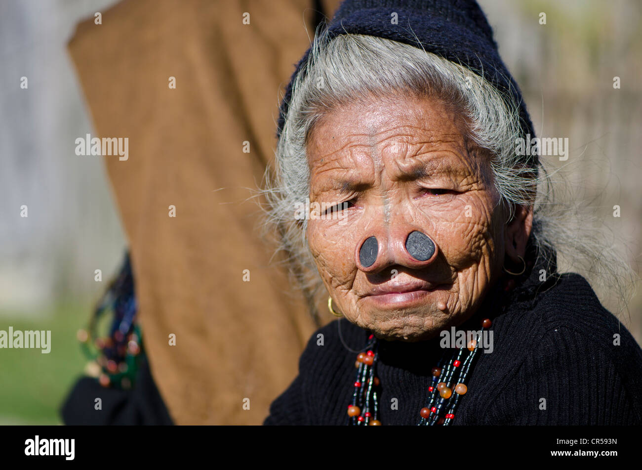 Vieille Femme Apatani avec le noseplugs traditionnel et tatouages, devant sa maison, Dutta village, de l'Arunachal Pradesh, Inde Banque D'Images