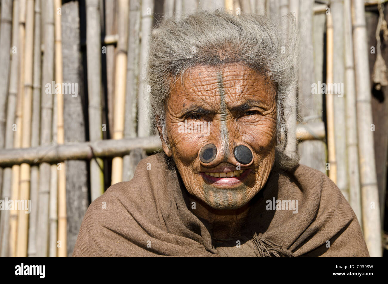 Vieille Femme Apatani avec le noseplugs traditionnel et tatouages, devant sa maison, Hong village, de l'Arunachal Pradesh, Inde Banque D'Images