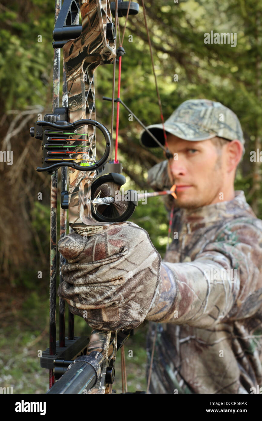 Beau bow hunter in camouflage tirant arc au fond des bois Photo Stock -  Alamy
