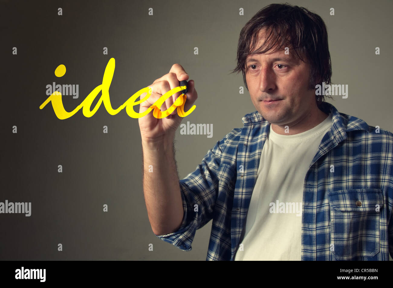 Designer occasionnels des jeunes adultes d'écrire le mot 'Idée' avec marqueur stylo jaune dans l'air. Banque D'Images