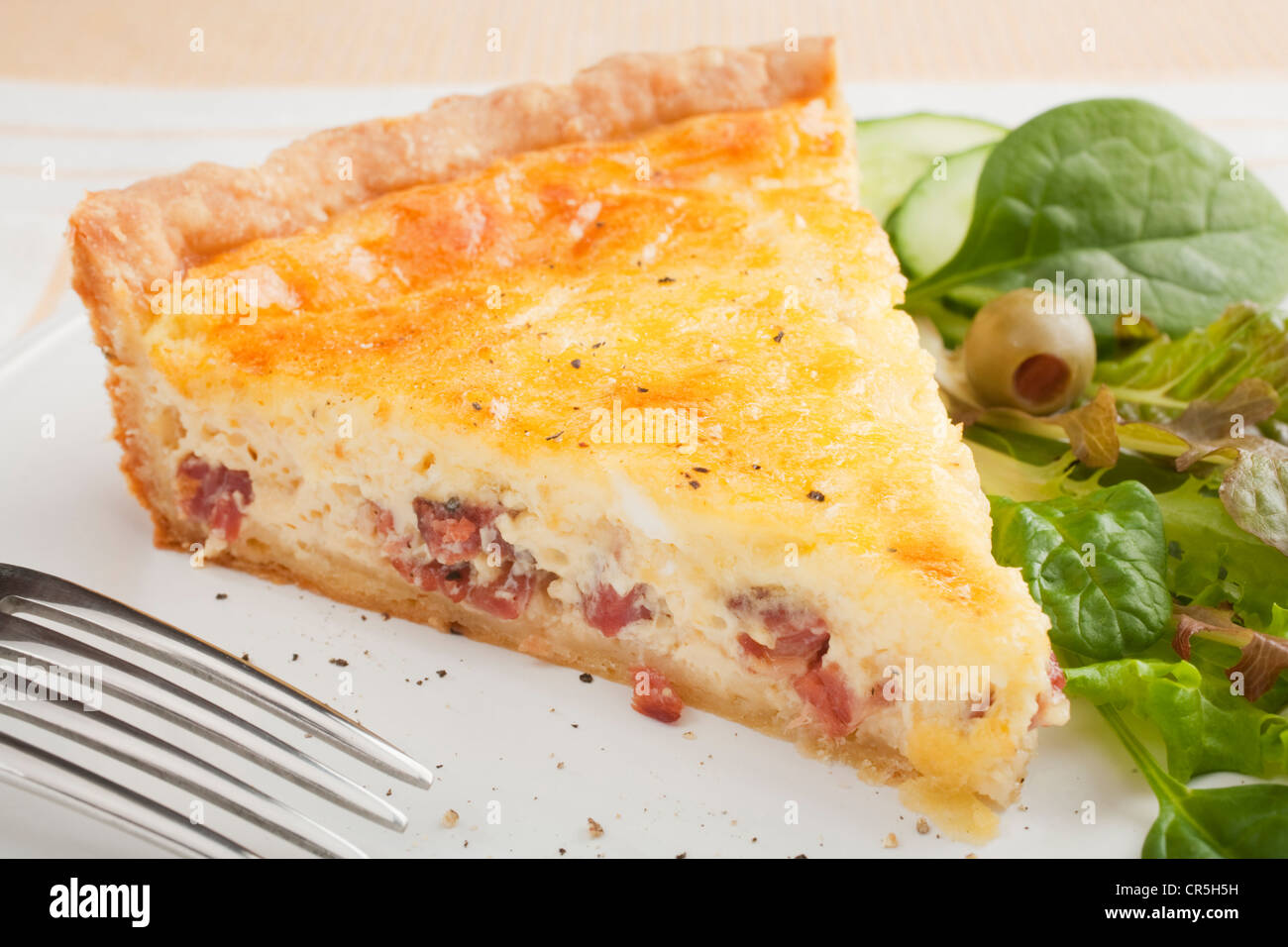 Une tranche de la quiche lorraine classique, ou du bacon et des oeufs, flan sur une assiette avec une salade verte. Banque D'Images