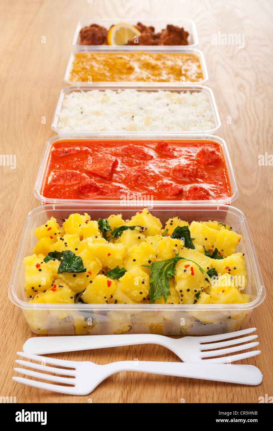 Une sélection des affaires indiennes de la nourriture à emporter dans des contenants de plastique sur une table en bois Banque D'Images