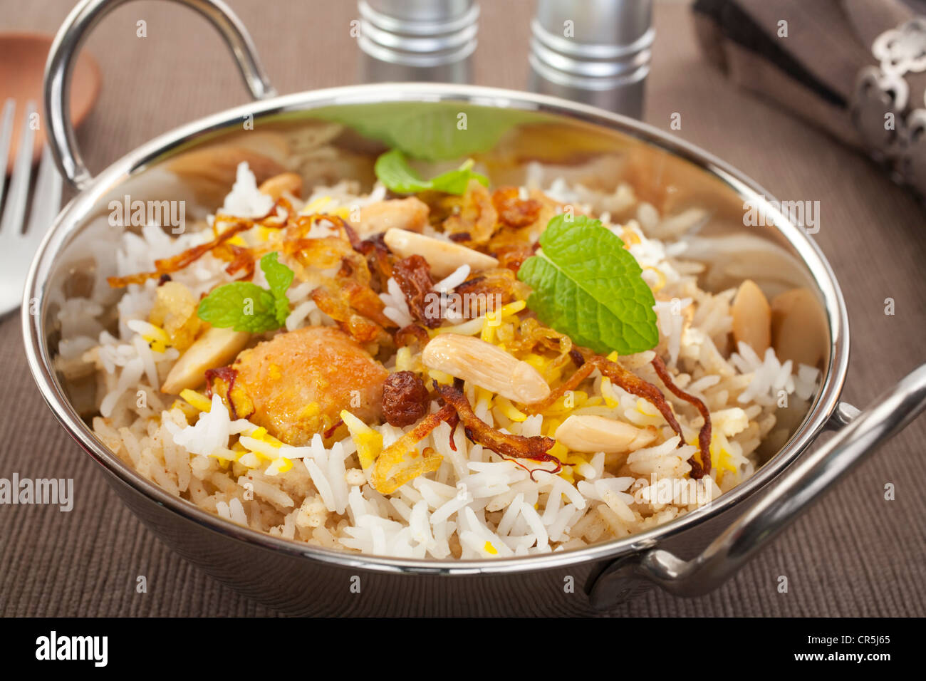 Occasion spéciale indien lave, poulet biryani est garnie avec des oignons frits, des raisins secs, les amandes et la menthe. Banque D'Images
