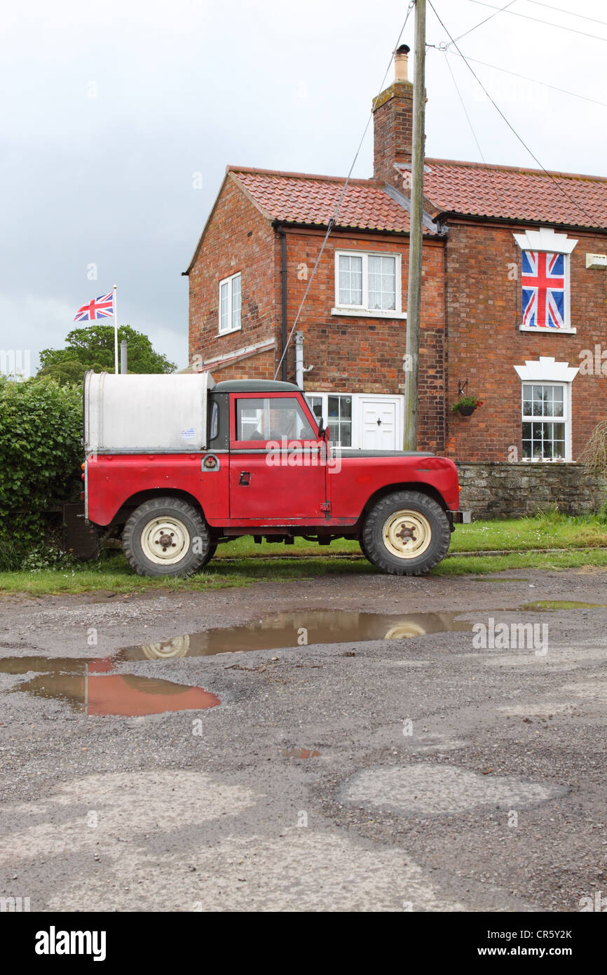 Land Rover véhicule stationné à l'extérieur de la maison avec les drapeaux Union Jack Banque D'Images