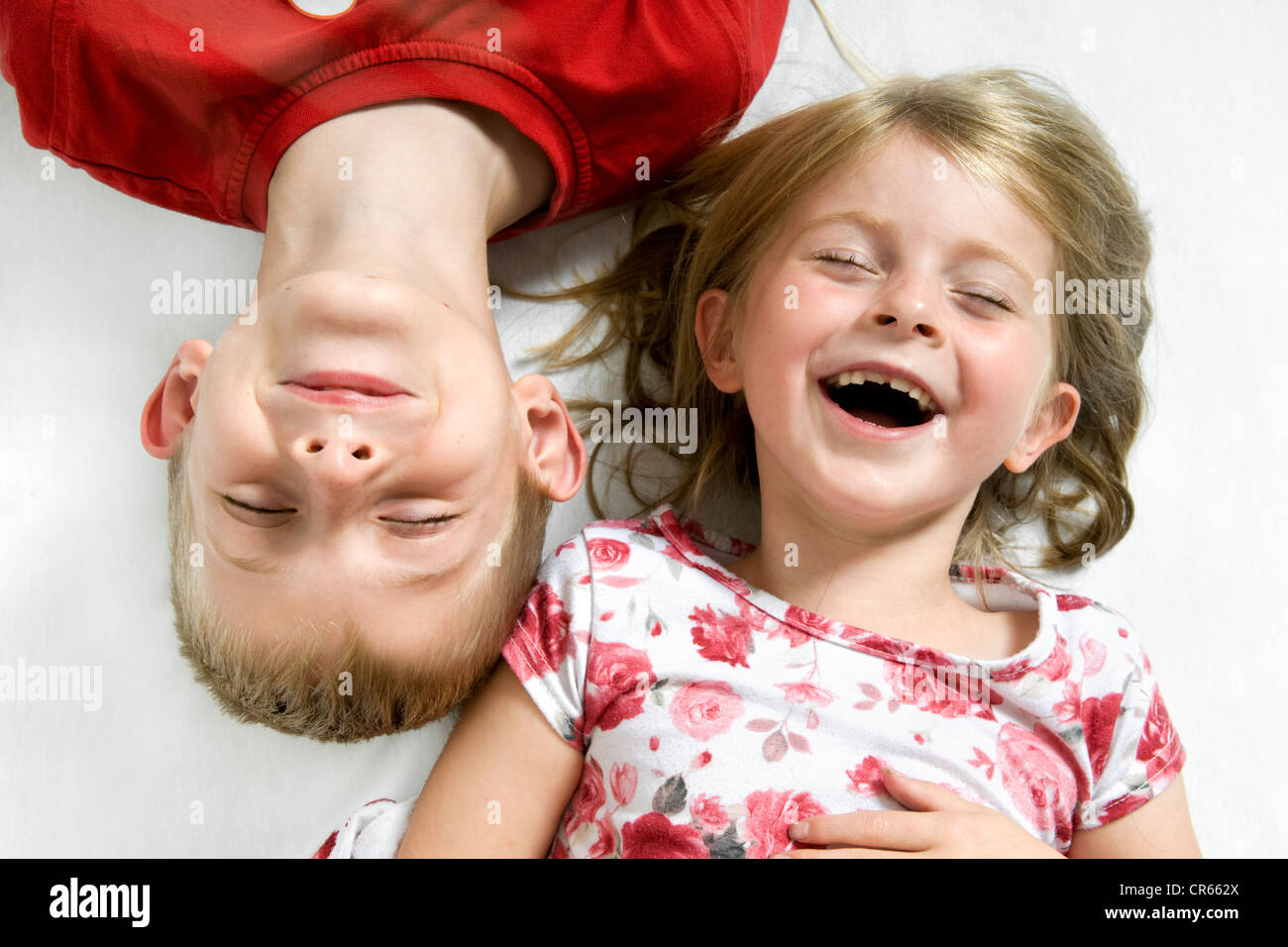 Deux des enfants de race blanche, un frère et une sœur s'amusant (7 ans, fille et garçon de 8 ans) sur un fond blanc Banque D'Images
