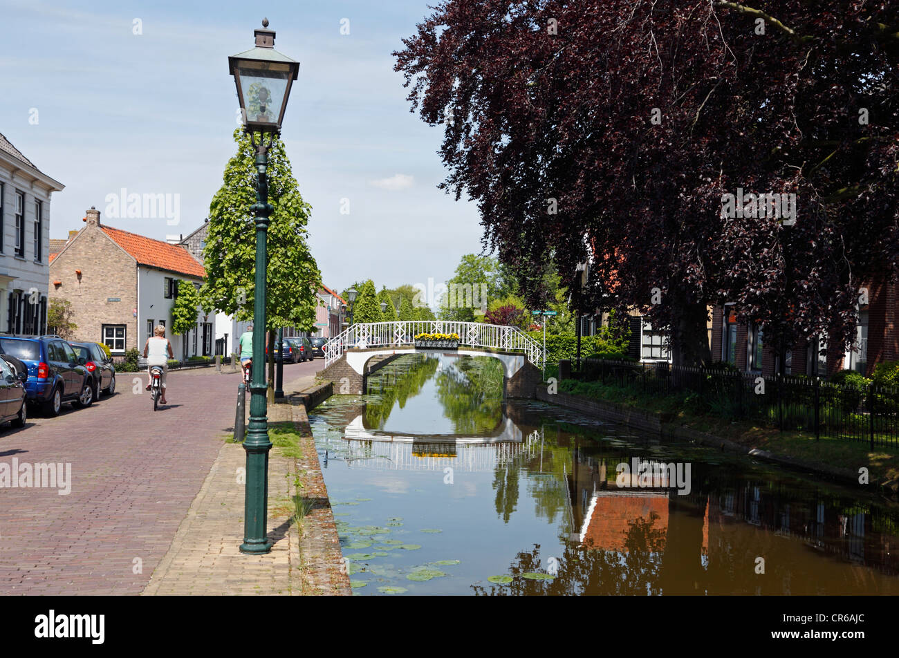 Les cyclistes en zone résidentielle, route et Pont sur canal dans la petite ville de Maasland, aux Pays-Bas. Banque D'Images