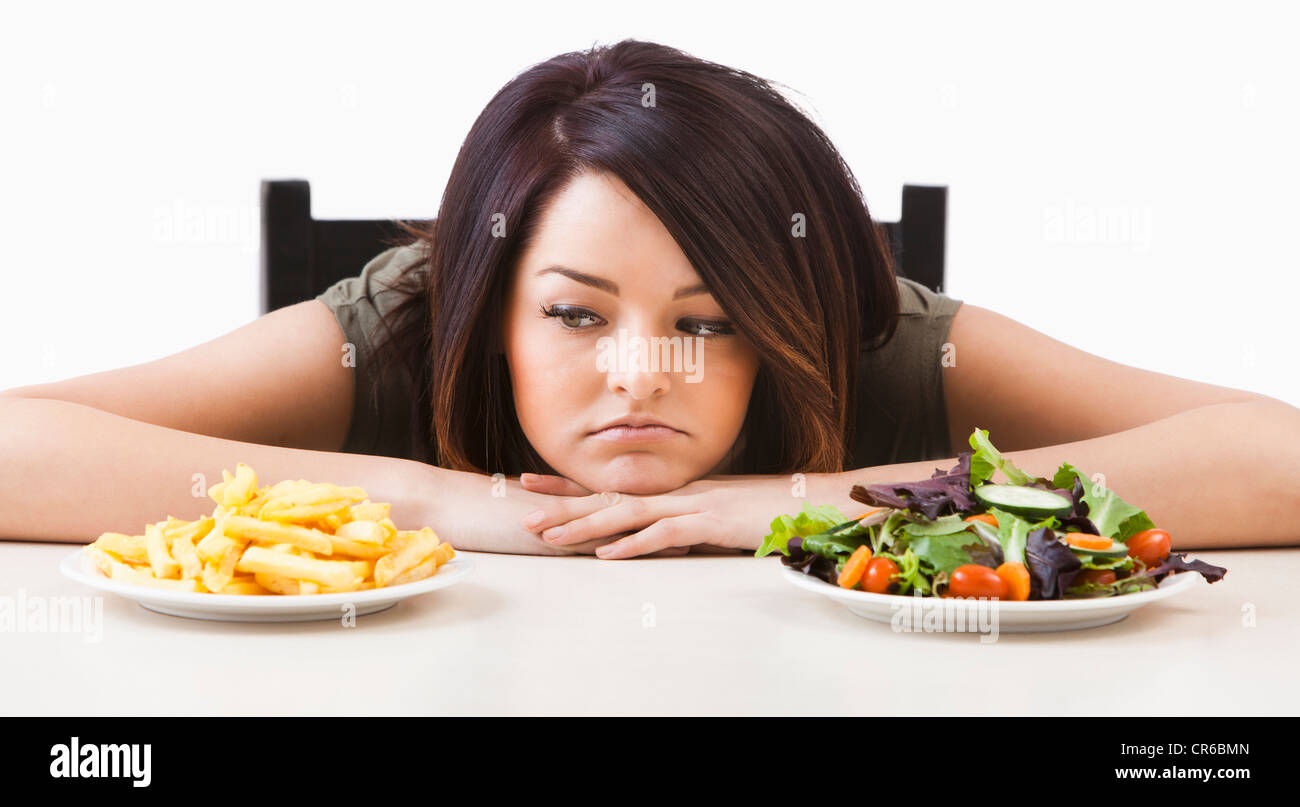 Jeune femme de choisir entre les aliments sains et malsains Banque D'Images